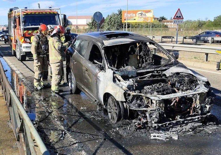 Los bomberos, junto al coche calcinado.