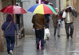 Varias personas caminan por la calle San Francisco en pleno diluvio.