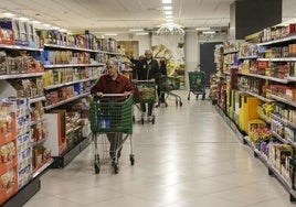 Varias personas hacen la compra en el interior de un supermercado.