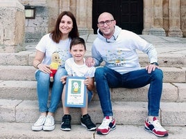 Manuel, junto a sus padres, sujeta un libro que divulga su enfermedad.