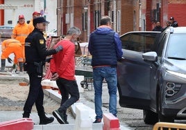 Agentes de la Policía Nacional introducen al detenido en un vehículo ante la atenta mirada de los obreros de la calle Ebro.