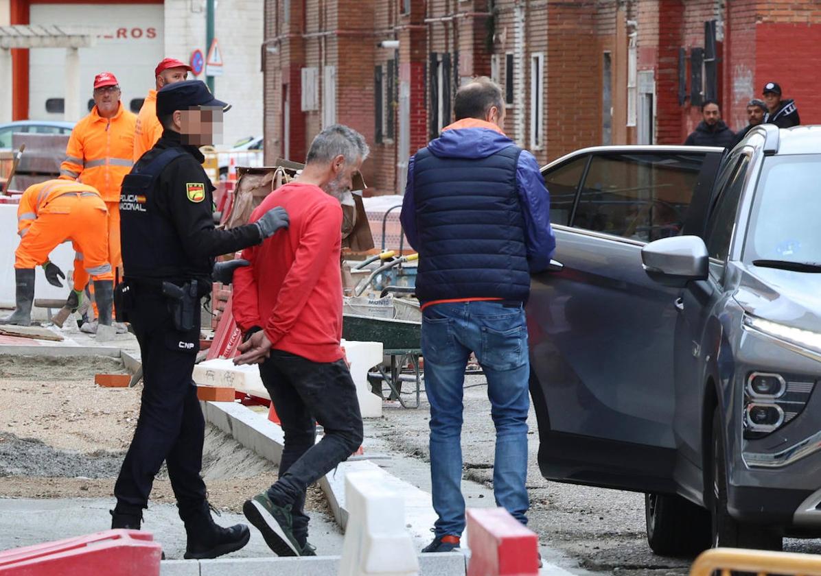 Agentes de la Policía Nacional introducen al detenido en un vehículo ante la atenta mirada de los obreros de la calle Ebro.