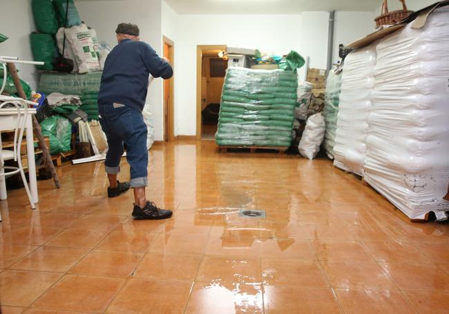 Un vecino achica agua del garaje de su vivienda.