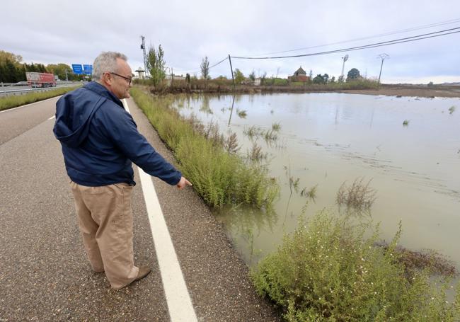 Jesús Medina muestra como el agua está a punto de desbordarse hacia la carretera