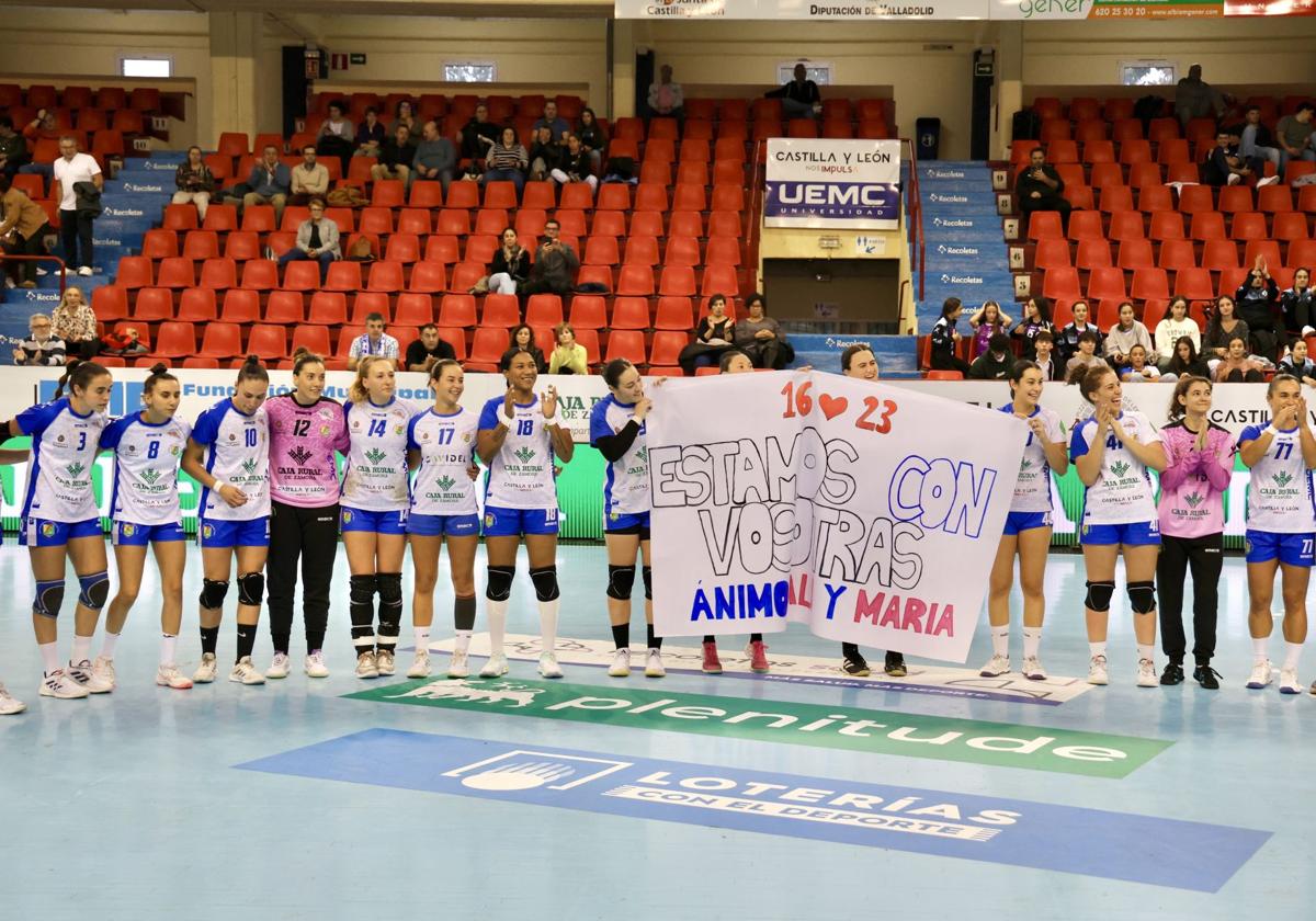 Las jugadoras del Aula portan una pancarta de ánimo a sus compañeras lesionadas antes del encuentro.