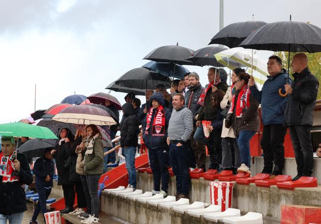 Los aficionados se protegen de la lluvia.