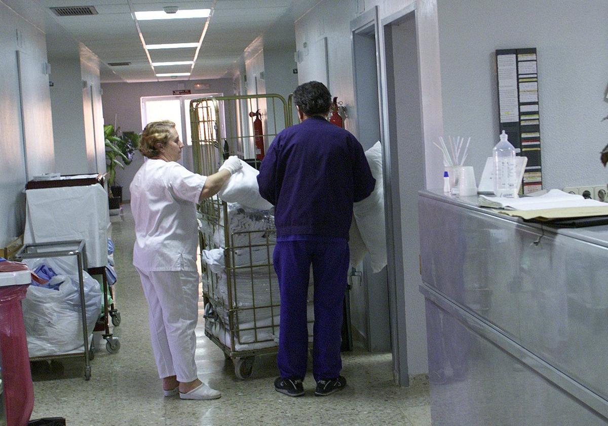 Imagen de archivo de una técnico en cuidados de enfermería repartiendo ropa de cama y aseo en un hospital.