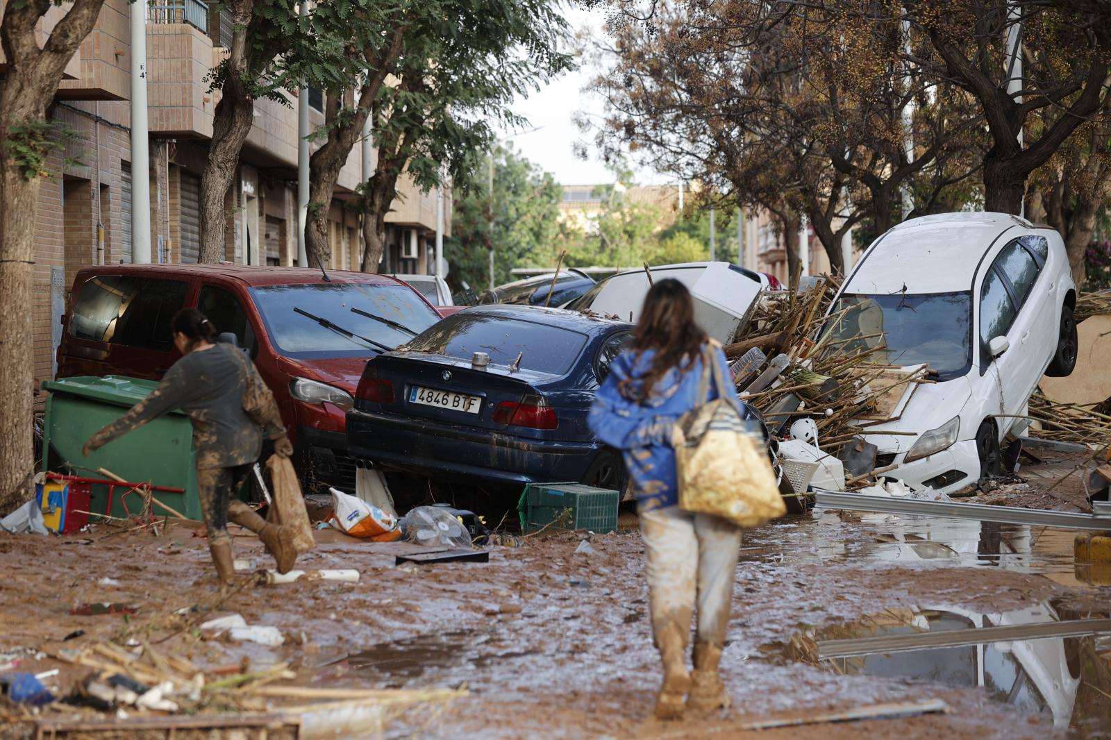 Varias personas caminan entre el lodo acumulado en las calles a causa de las intensas lluvias caídas por la fuerte dana, este jueves en Catarroja (Valencia).