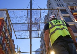 Un operario monta los adornos en los pórticos de la calle Santiago.