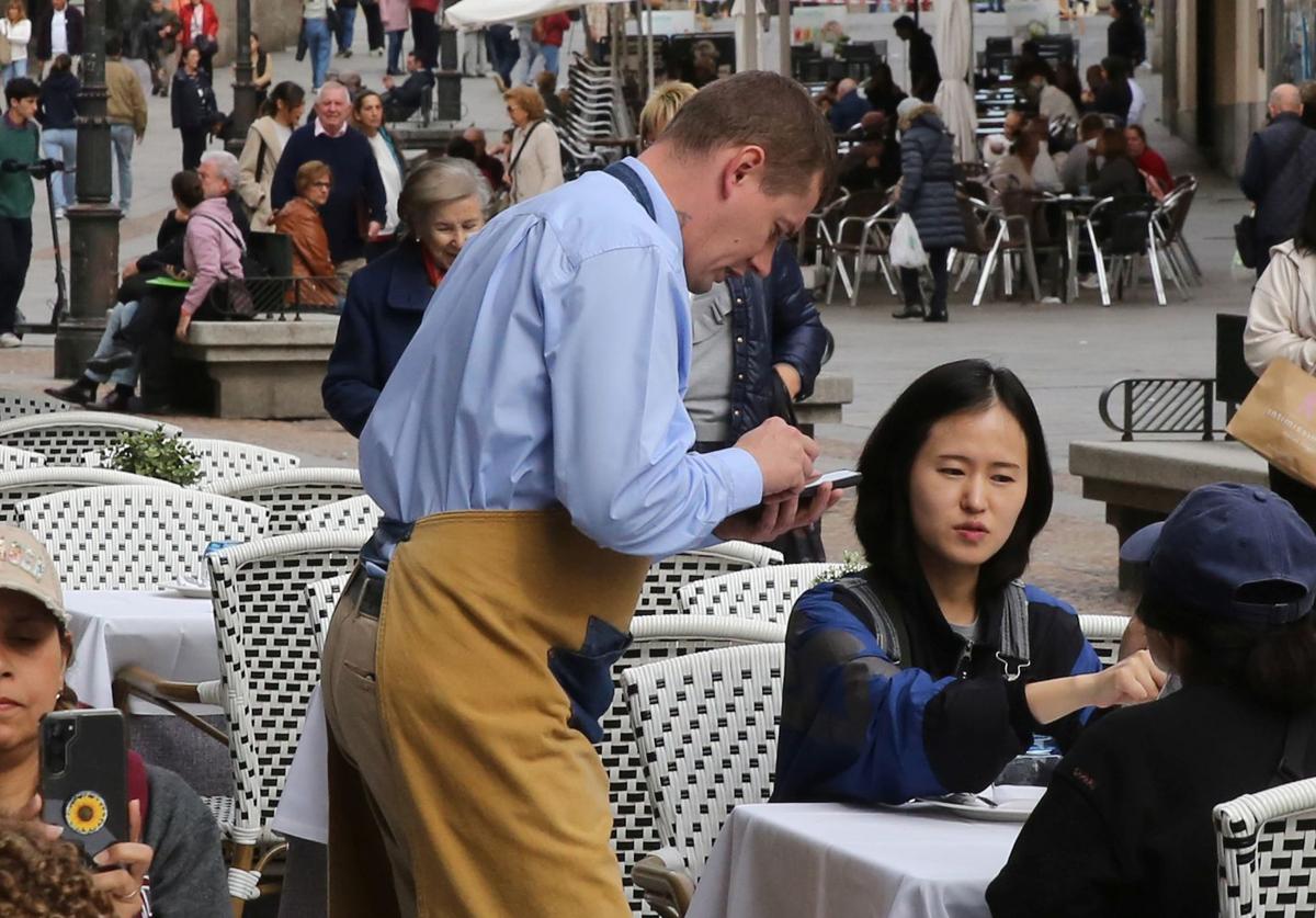 Un camarero toma la comanda a unas turistas en un restaurante de Segovia.