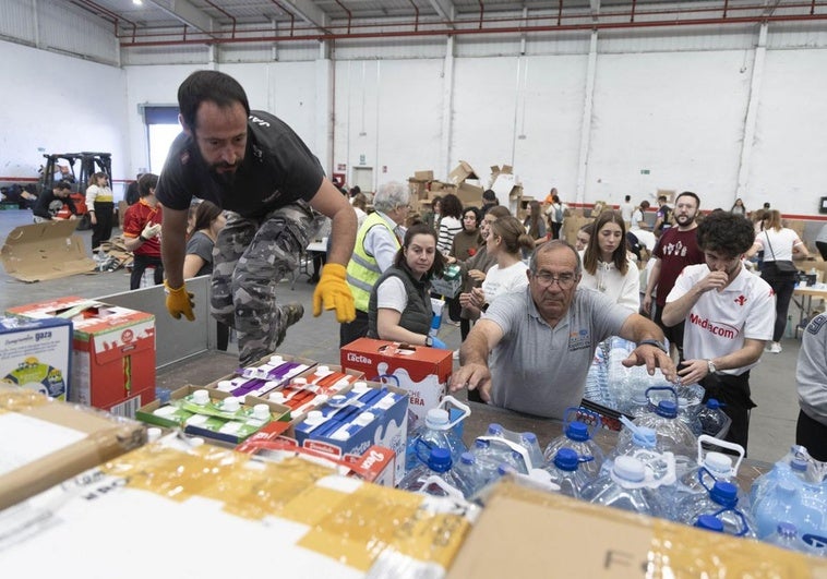 Varias personas descargan en la nave de La Cistérniga un camión lleno de productos destinados a los damnificados por la DANA en Valencia.