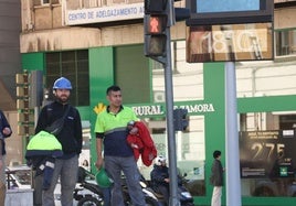 El termómetro de plaza España registra la mañana del 6 de noviembre 18 grados, mientras unos operarios esperan el semáforo con la chaqueta en la mano.