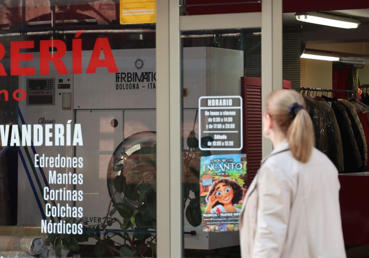 Una mujer pasa por delante de una lavandería en Palencia.