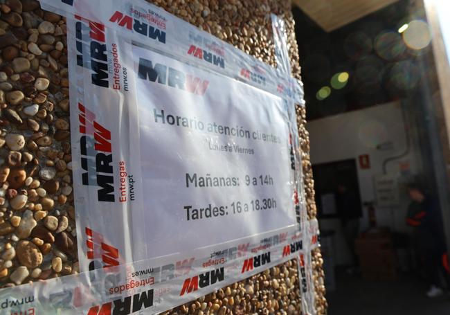 Cartel con los horarios de atención al público en el exterior de la nave de la calle Aluminio, 9.