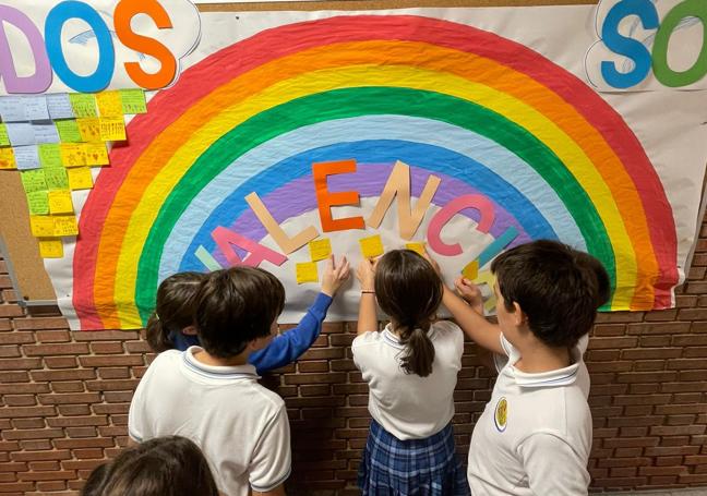 Un grupo de alumnos del colegio El Carmen trabajan sobre un mural en el que se puede leer 'Valencia somos todos'