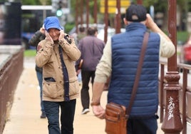 Un hombre se protege del viento en el Puente Mayor durante el último vendaval de octubre.