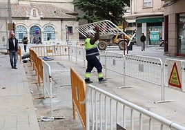 Un trabajador de DH Ecoenergías retira vallas de la calle San Juan de Dios.