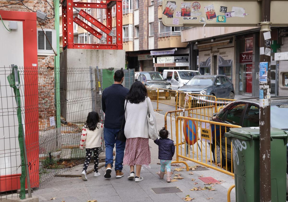 Imagen principal - Una familia camina por el acceso peatonal junto al edifcio. La antena decolgada sobre el tejado y parte de la chimenea que se desprendió el 3 de noviembre.