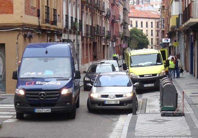 Una furgoneta esquiva a un coche aparcado en doble fila delante de otro furgón parado sobre la acera de la calle Ferrocarril.