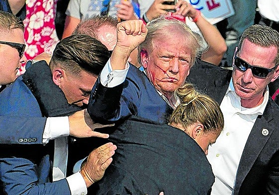 Trump, con la cara ensangrentada, es trasladado segundos después del atentado que sufrió en Pensilvania el 14 de julio.