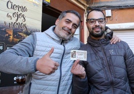 Vecinos de Ayllón enseñan uno de los décimos agraciados con el cuarto premio de la Lotería de Navidad.