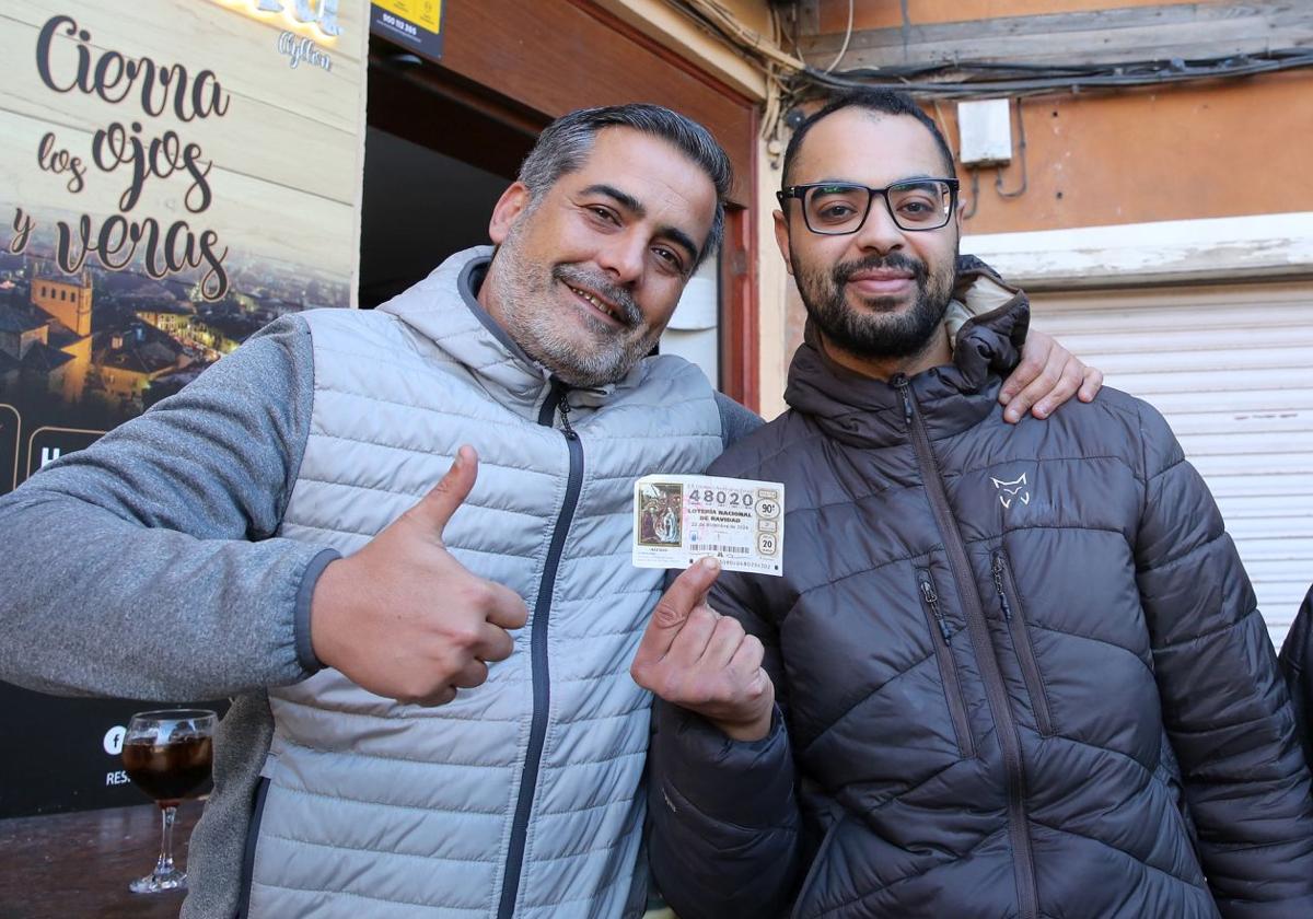 Vecinos de Ayllón enseñan uno de los décimos agraciados con el cuarto premio de la Lotería de Navidad.