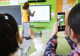 Dos alumnas utilizan el teléfono móvil en un aula en Castilla y León.