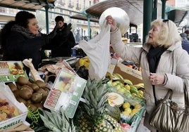 La frutera Soraya Sastre entrega la bolsa con las uvas a Merche, una de sus clientas.