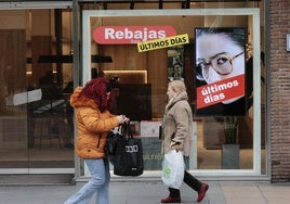 Dos mujeres pasan frente a un escaparate que anuncia rebajas.