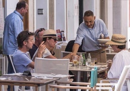 Un camarero atiende a unos clientes en la terraza de un bar.