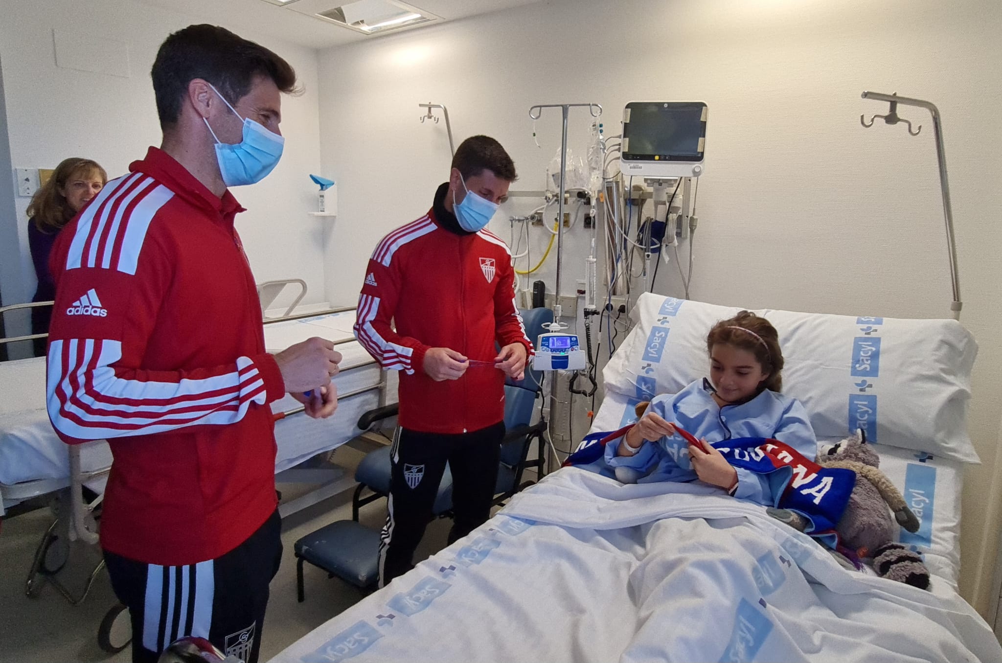 Fer Llorente y Manu regalan a una niña una bufanda de la Segoviana.