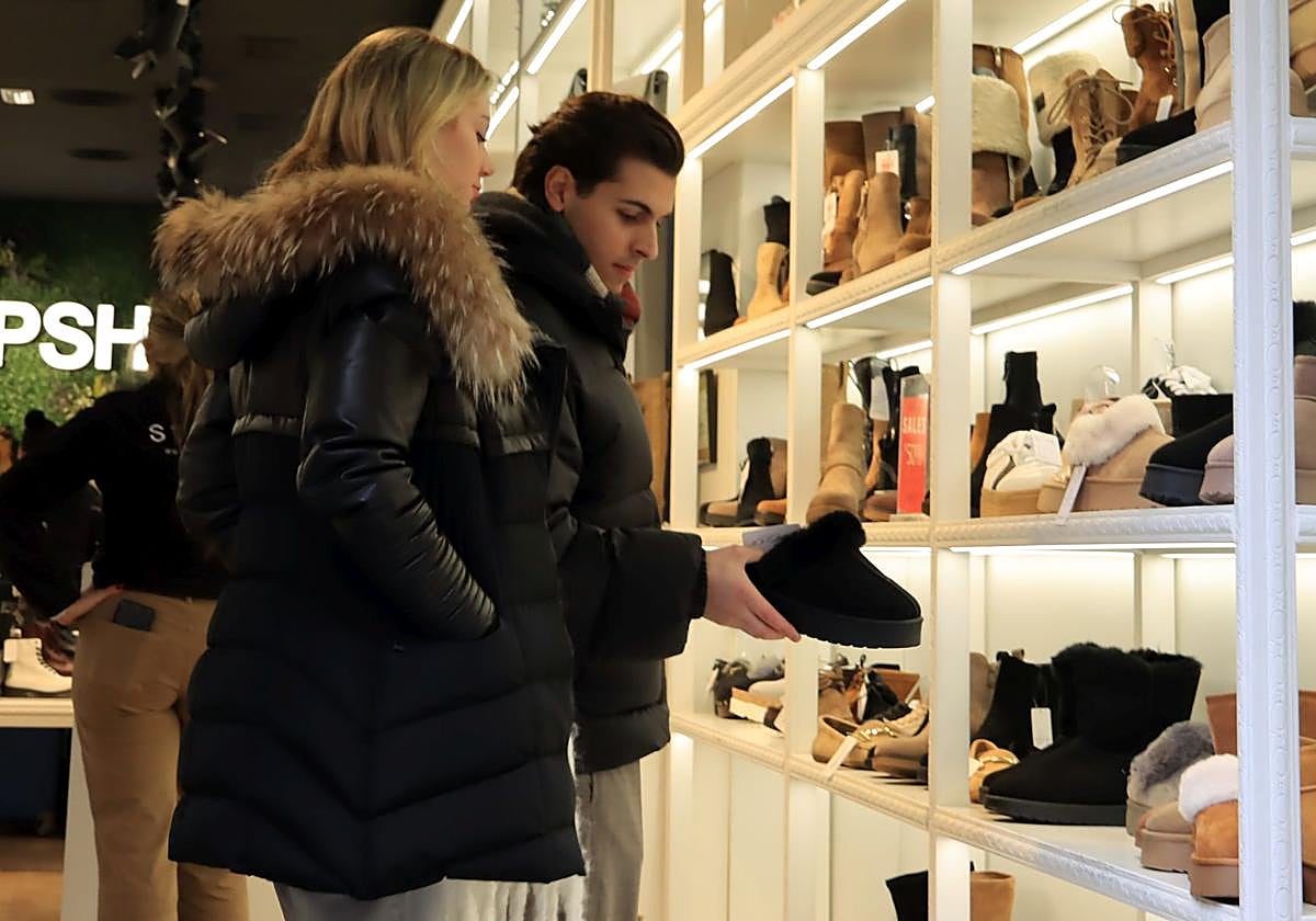 Dos clientes observan productos en una tienda de calzado de Segovia.