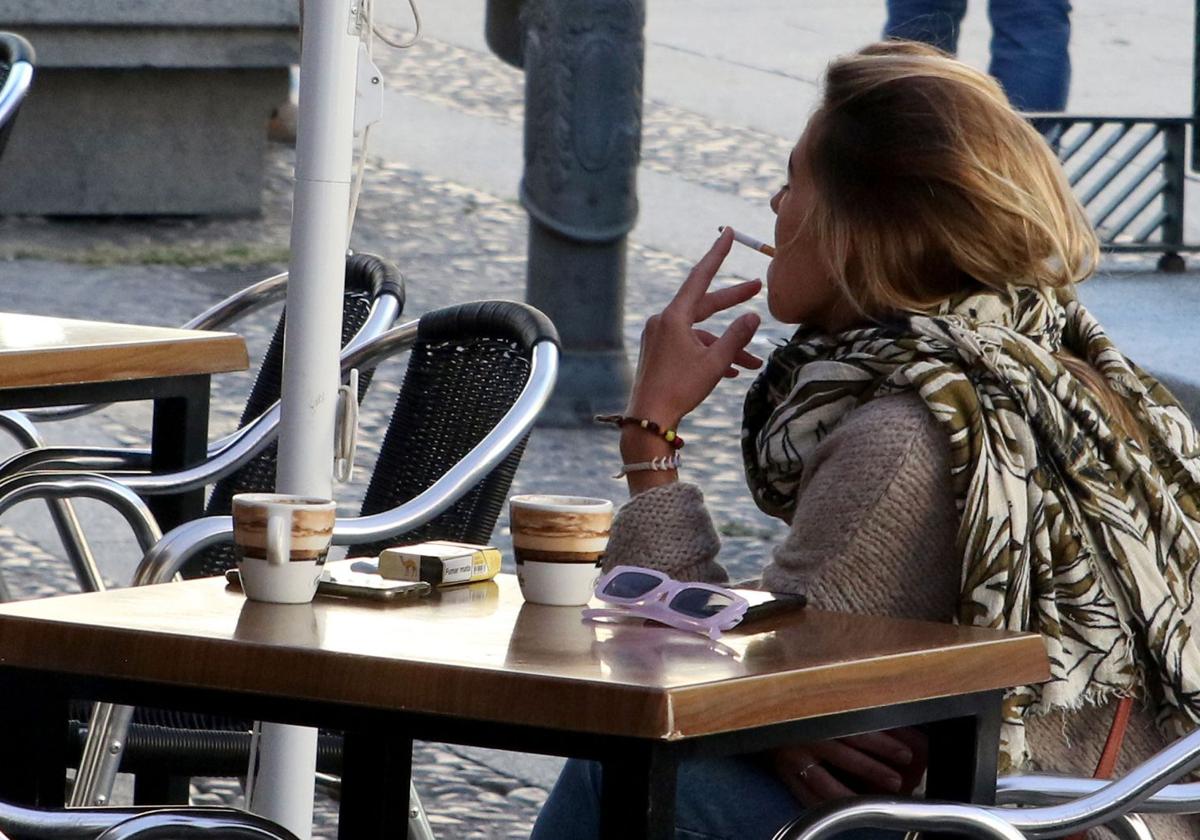 Una mujer fuma un cigarro en una terraza de un bar de Segovia.