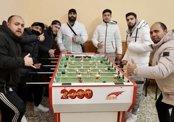 Varios jugadores y entrenadores del Club Santo Toribio-Cáritas juegan al futbolín en los locales de la parroquia.