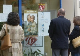 Unas personas miran un cartel del Club de los 60 en Valladolid.