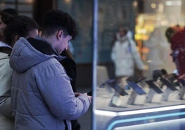 Una pareja de jóvenes delante del escaparate de una tienda de telefonía de Valladolid este miércoles.