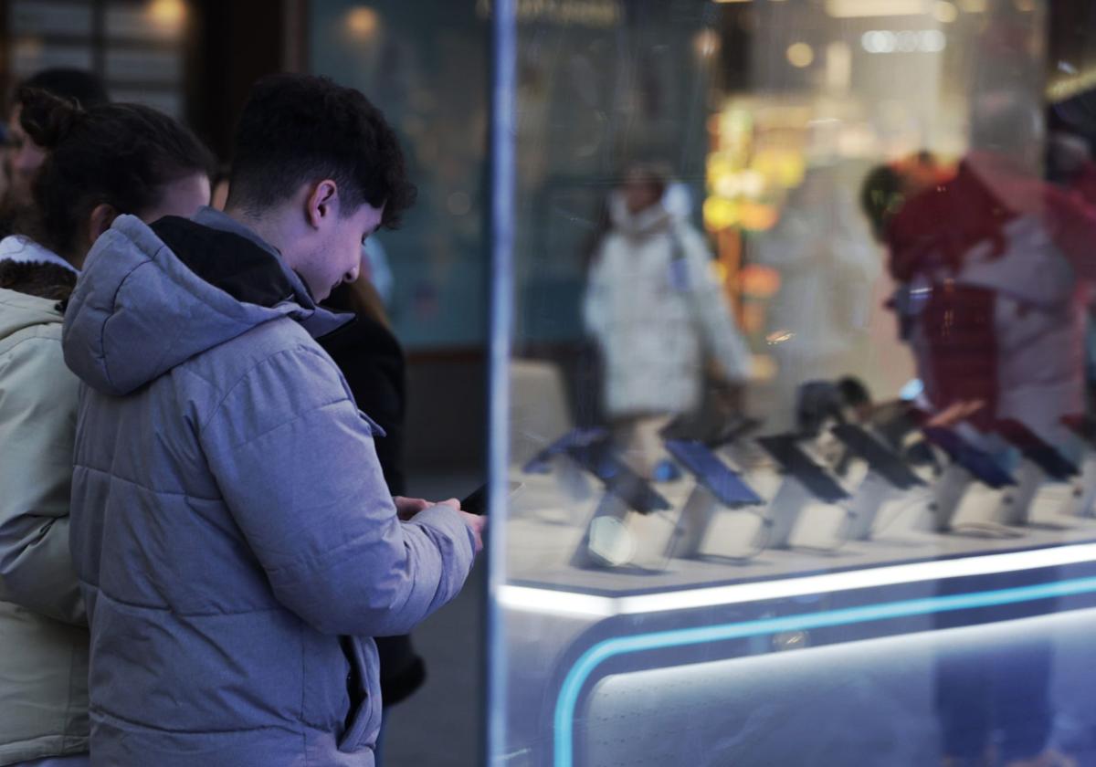 Una pareja de jóvenes delante del escaparate de una tienda de telefonía de Valladolid este miércoles.