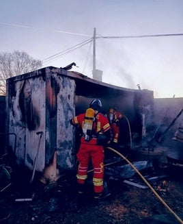 Los bomberos sofocan el incendio en la caseta.