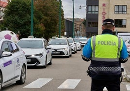 Un policía local regula el tráfico al paso de la caravana de taxis este miércoles en Valladolid.