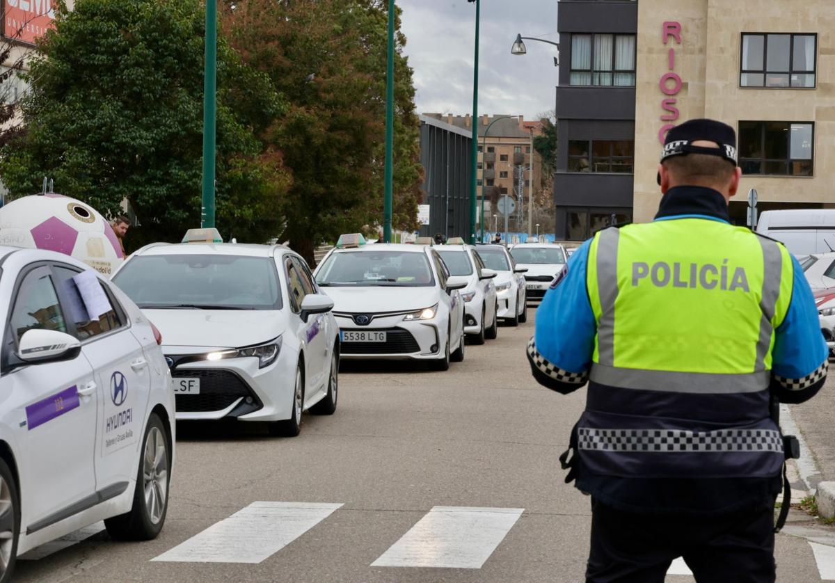 Un policía local regula el tráfico al paso de la caravana de taxis este miércoles en Valladolid.