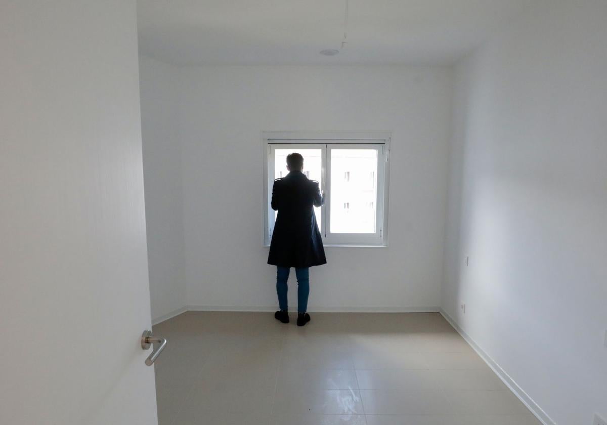 Un hombre mira por la ventana desde uno de los pisos promovidos por la Junta de Castilla y León en el antiguo cuartel de Puente Colgante, en Valladolid.