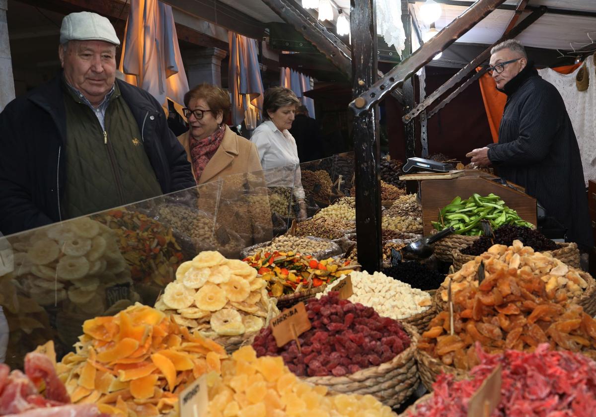 Varias personas pasan por un puesto de frutas deshidratadas, este viernes en el mercado de las Candelas de Palencia.