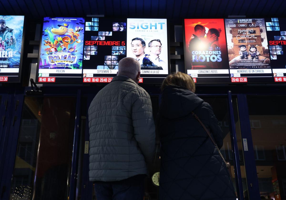 Dos espectadores observan las películas en cartelera a la entrada de los cines Broadway.