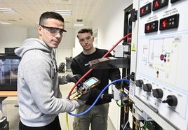 Dos jóvenes manipulan maquinaria en un aula de FP.