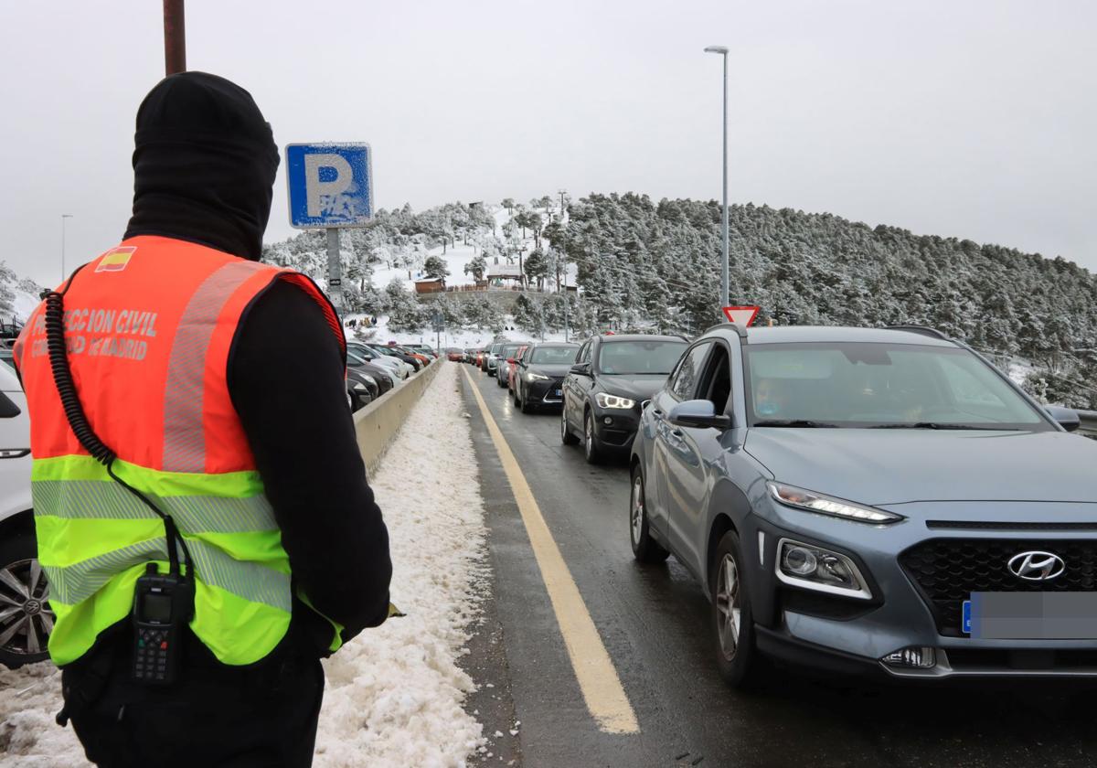 Un voluntario de Protección Civil regula el acceso a un aparcamiento de Navacerrada.