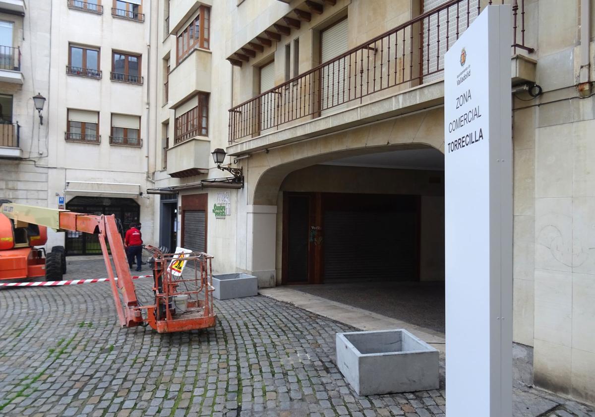 Imagen principal - Arriba, cartel y maceteros colocados en el acceso al pasadizo desde la plaza de Federico Watenberg. Debajo, a la izquierda, bancos de madera recién instalados sobre los antiguos bloques de piedra frente al Colegio de Abogados, A la derecha, maceteros frente al bar La Tartana.