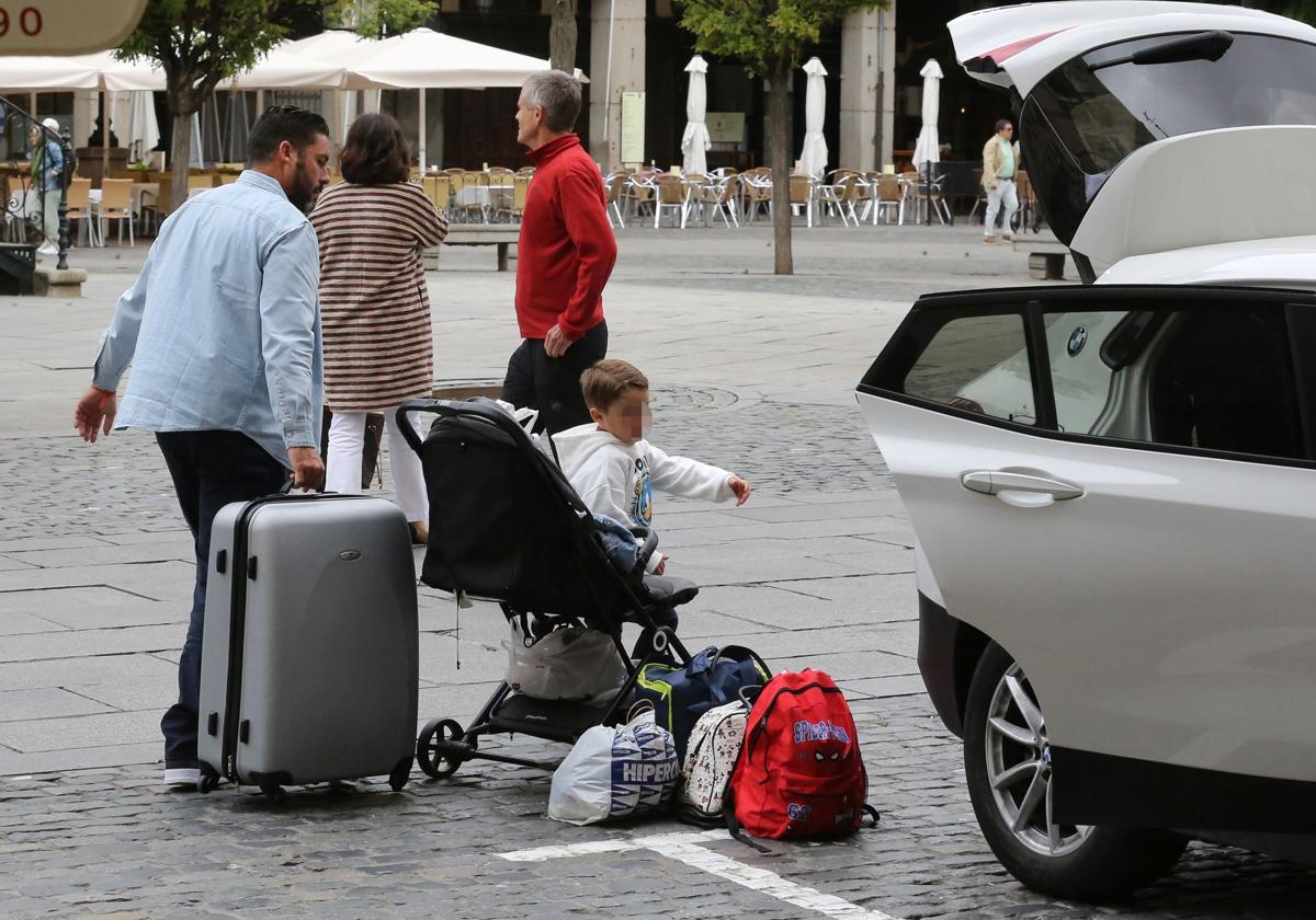 Turistas cargan las maletas en el coche en el centro de Segovia.