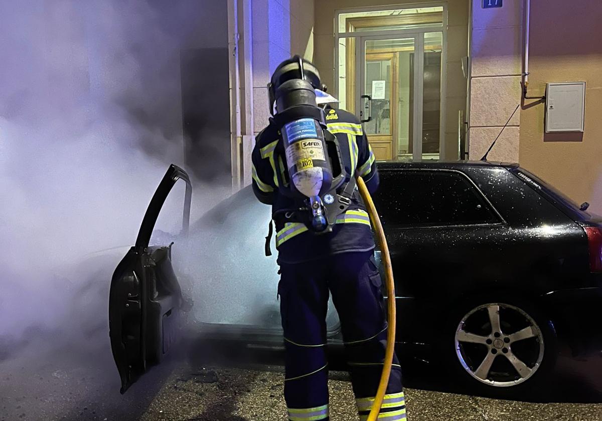 Un bombero del parque de Íscar sofoca el incendio en el vehículo, este martes de madrugada.