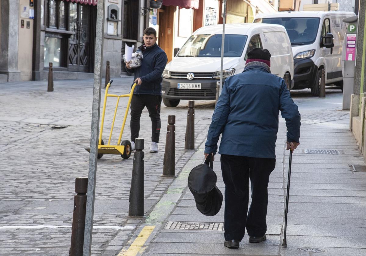 Una persona jubilada camina con su bastón frente a un joven trabajador.