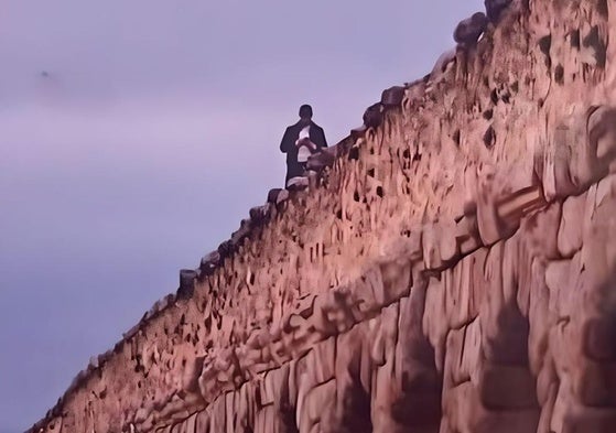 El hombre, subido en lo alto del Acueducto.